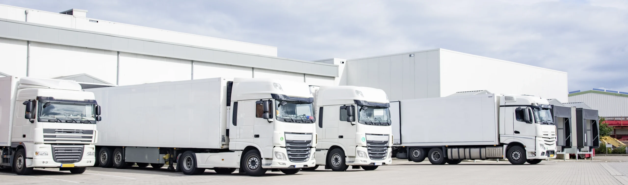Vier LKW stehen vor einer Halle